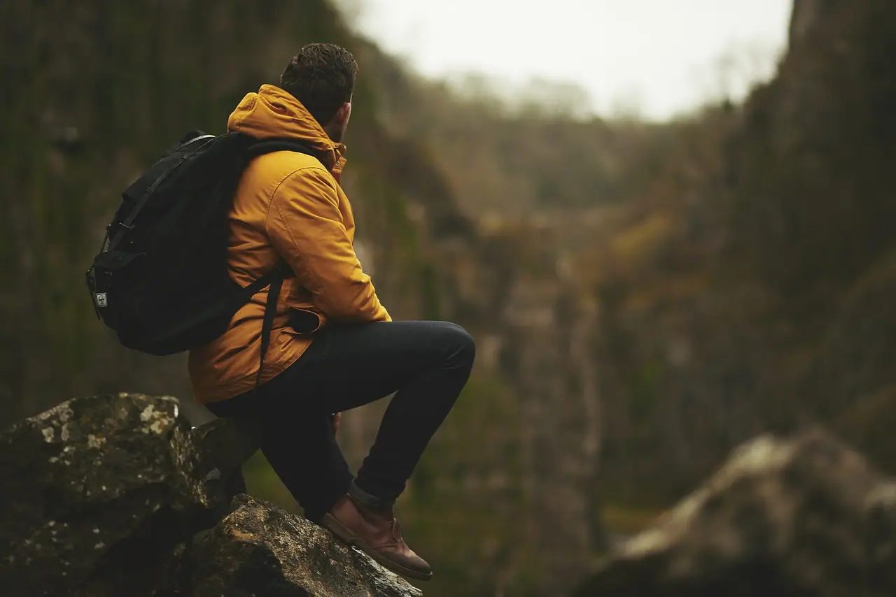 un uomo contempla il paesaggio col suo zaino da viaggio in spalla